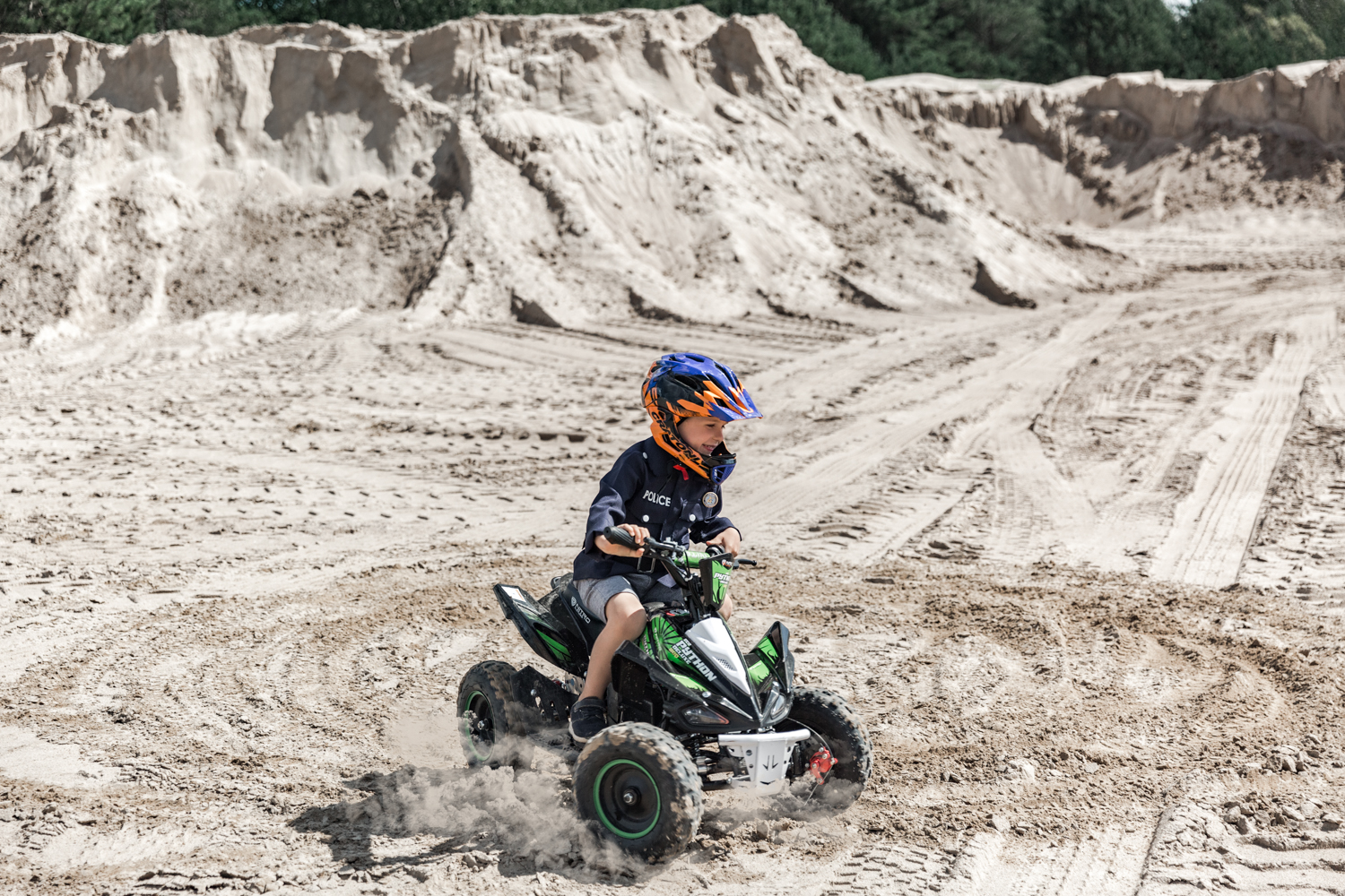 Berniukas ant keturračio daro saulę ant smėlio