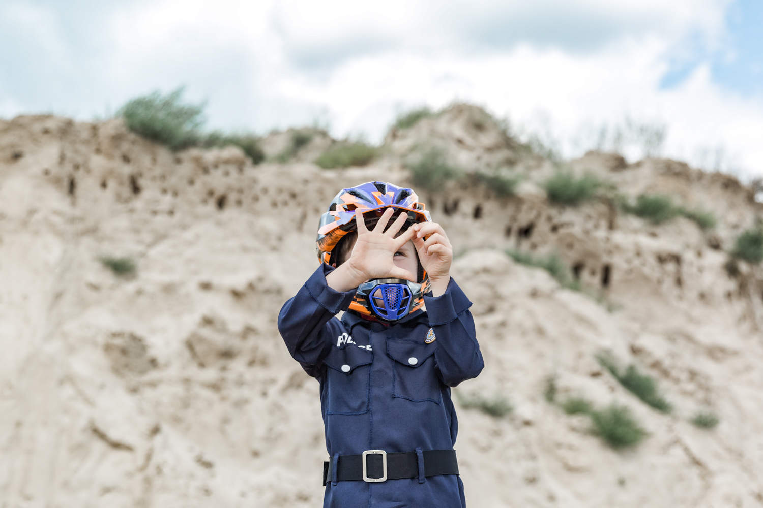 Policininko kostiumą apsivilkęs berniukas su šalmu, delnu rodo metų skaičių