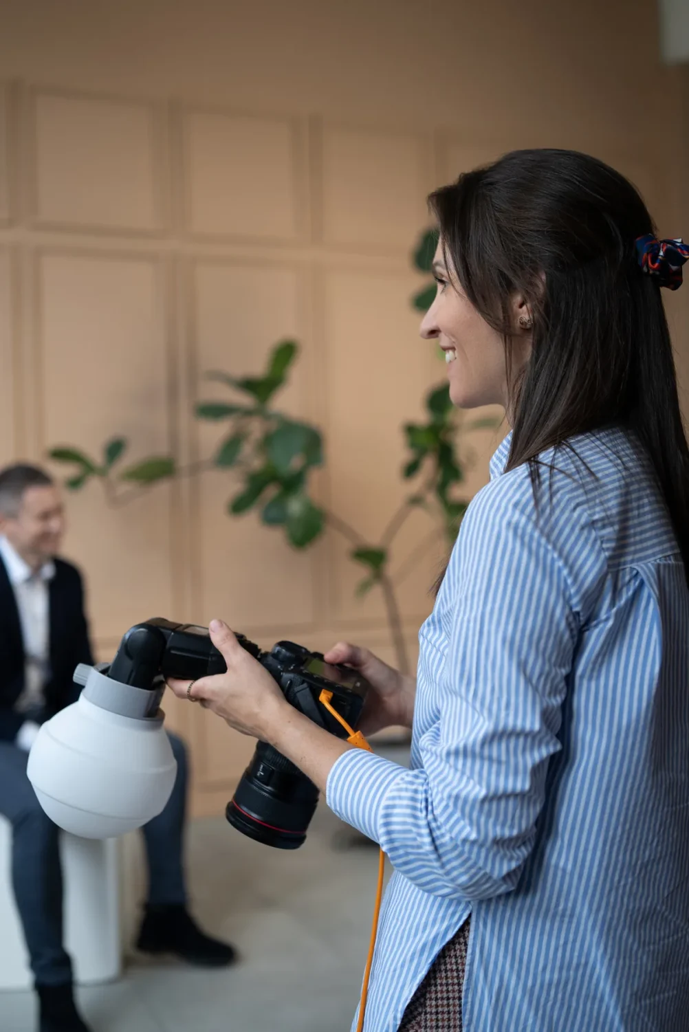 Fotografė Reda Ruzel verslo portreto fotosesijos metu: fone fotografuojamas vyras kostiumu